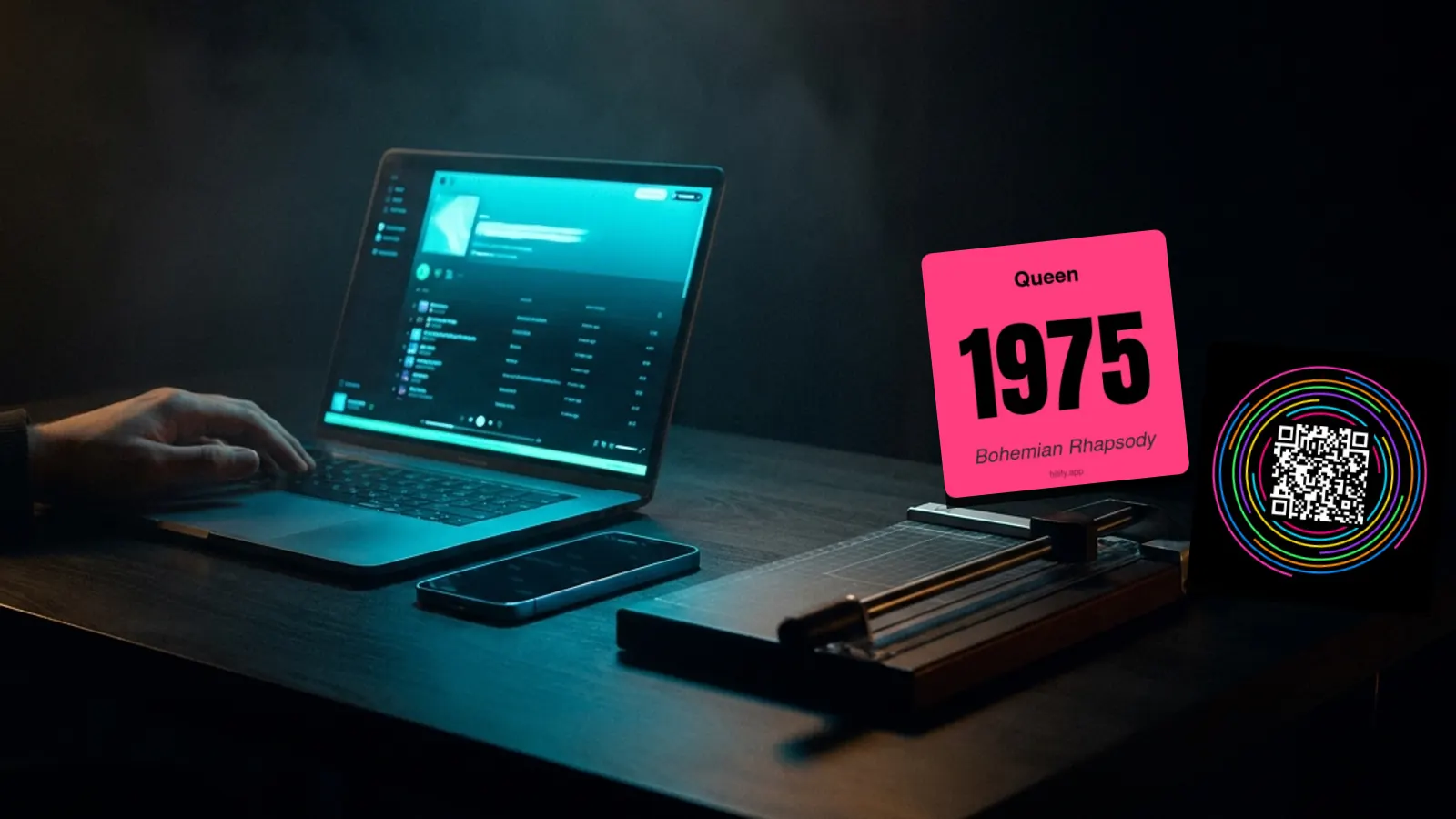 Hitify-musikkort, laptop och skrivare på ett mörkt skrivbord: Gör Ditt Eget Hitster Gratis: Den Kompletta Steg-för-Steg-Guiden